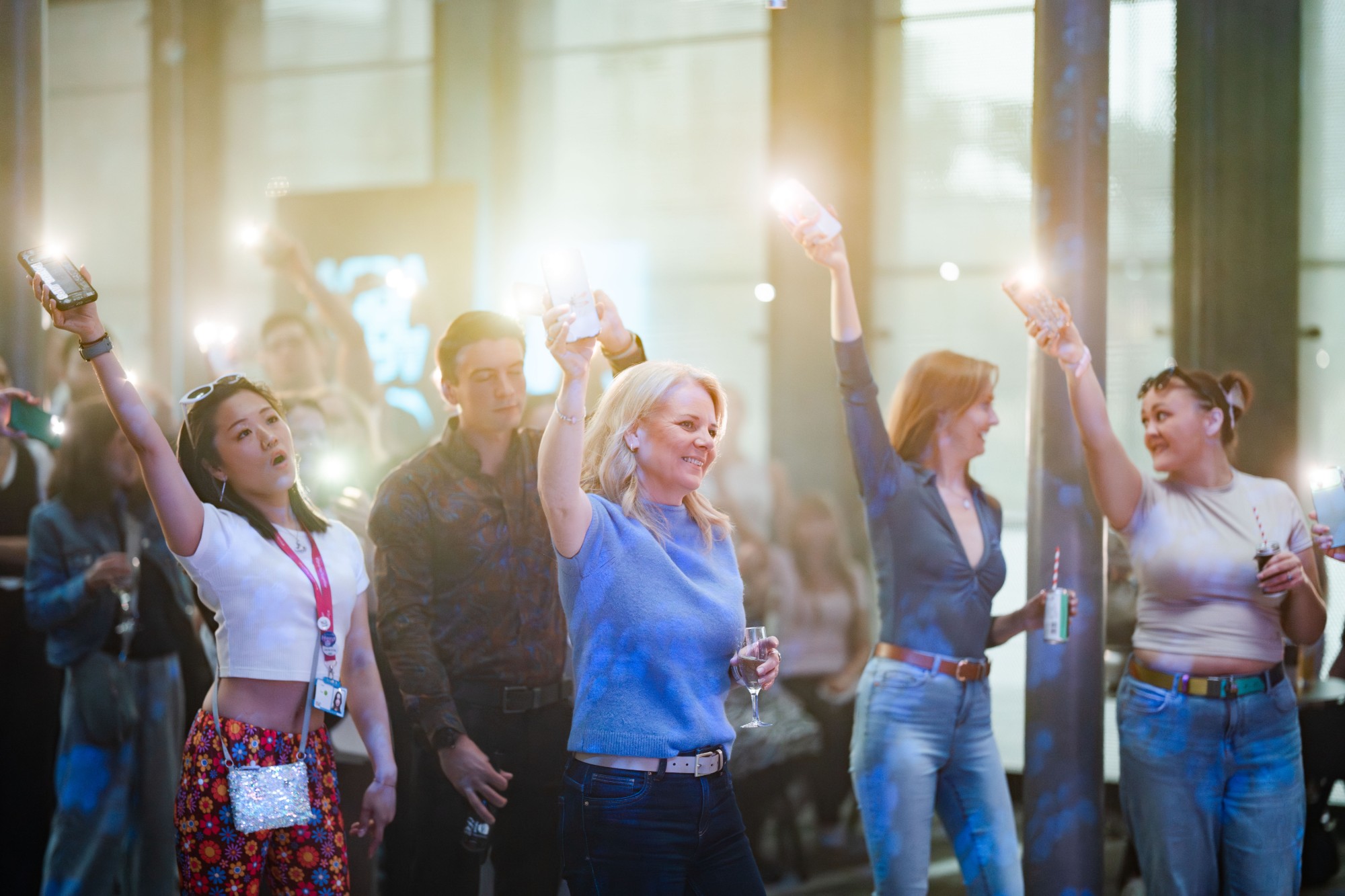 A crowd at an ABBA night at the Barclays campus holding phone torches in the air