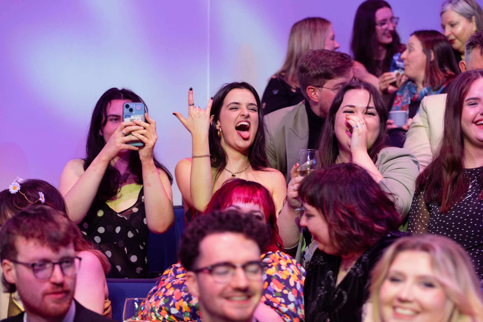 The crowd at the Film G Awards cheering and filming under purple light