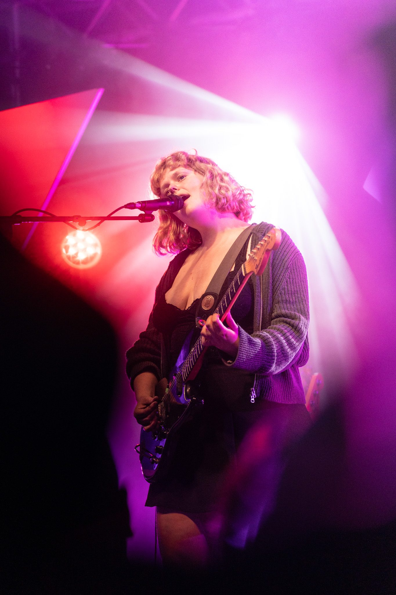 A singer with a guitar under pink stage light