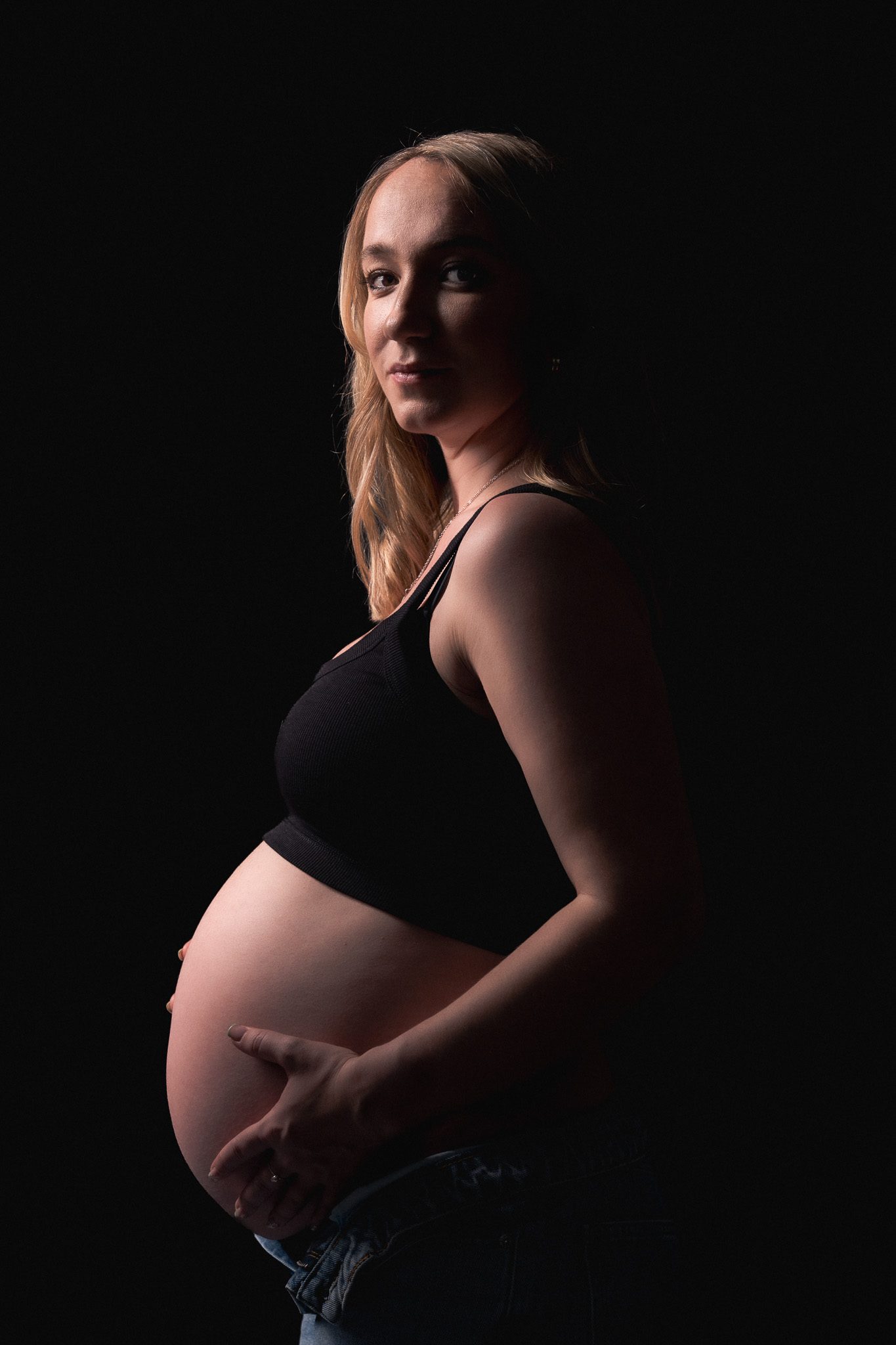 A maternity portrait in low studio light