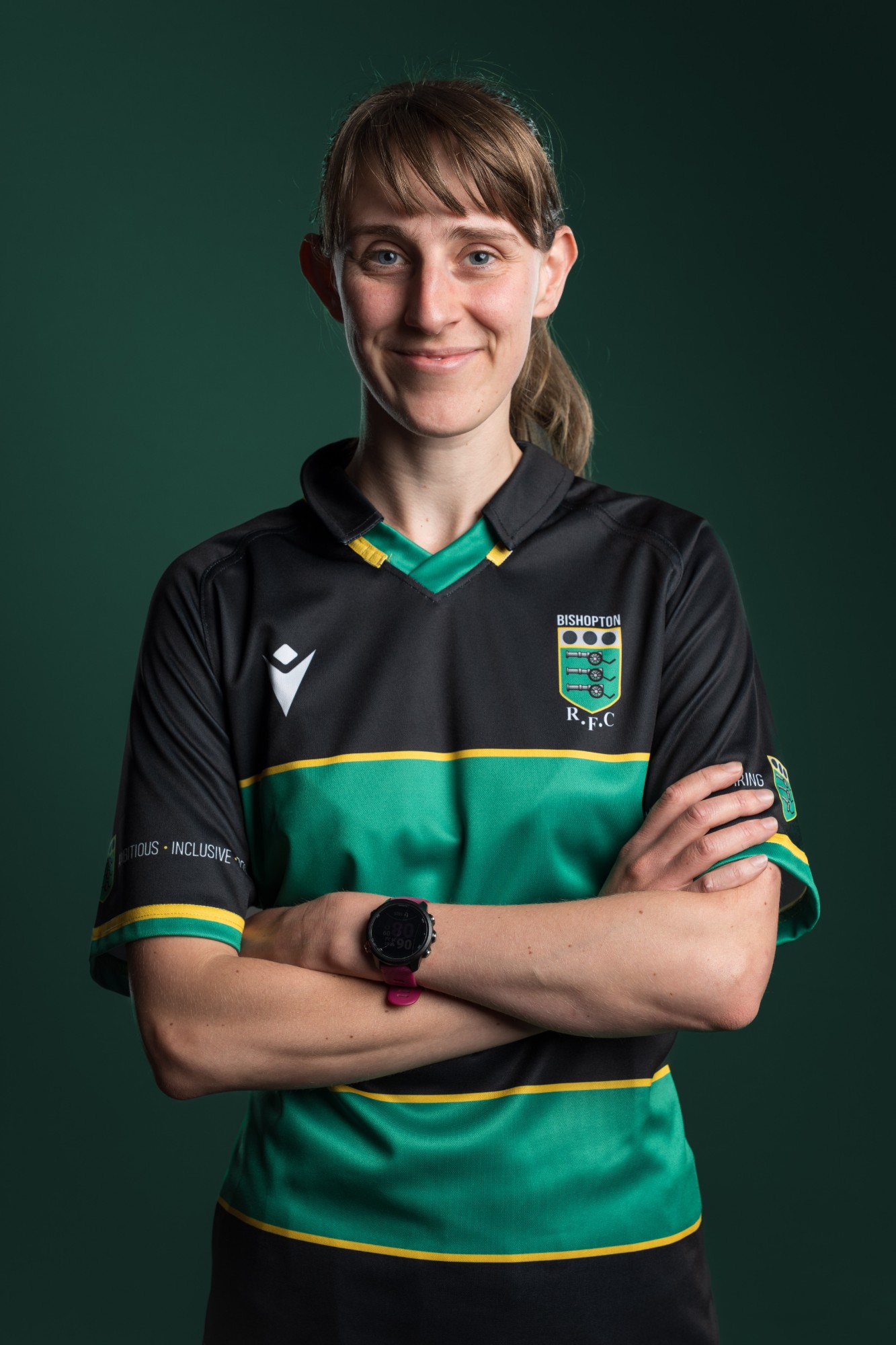 A woman in a Bishopton RFC shirt, arms folded, against a dark green backdrop