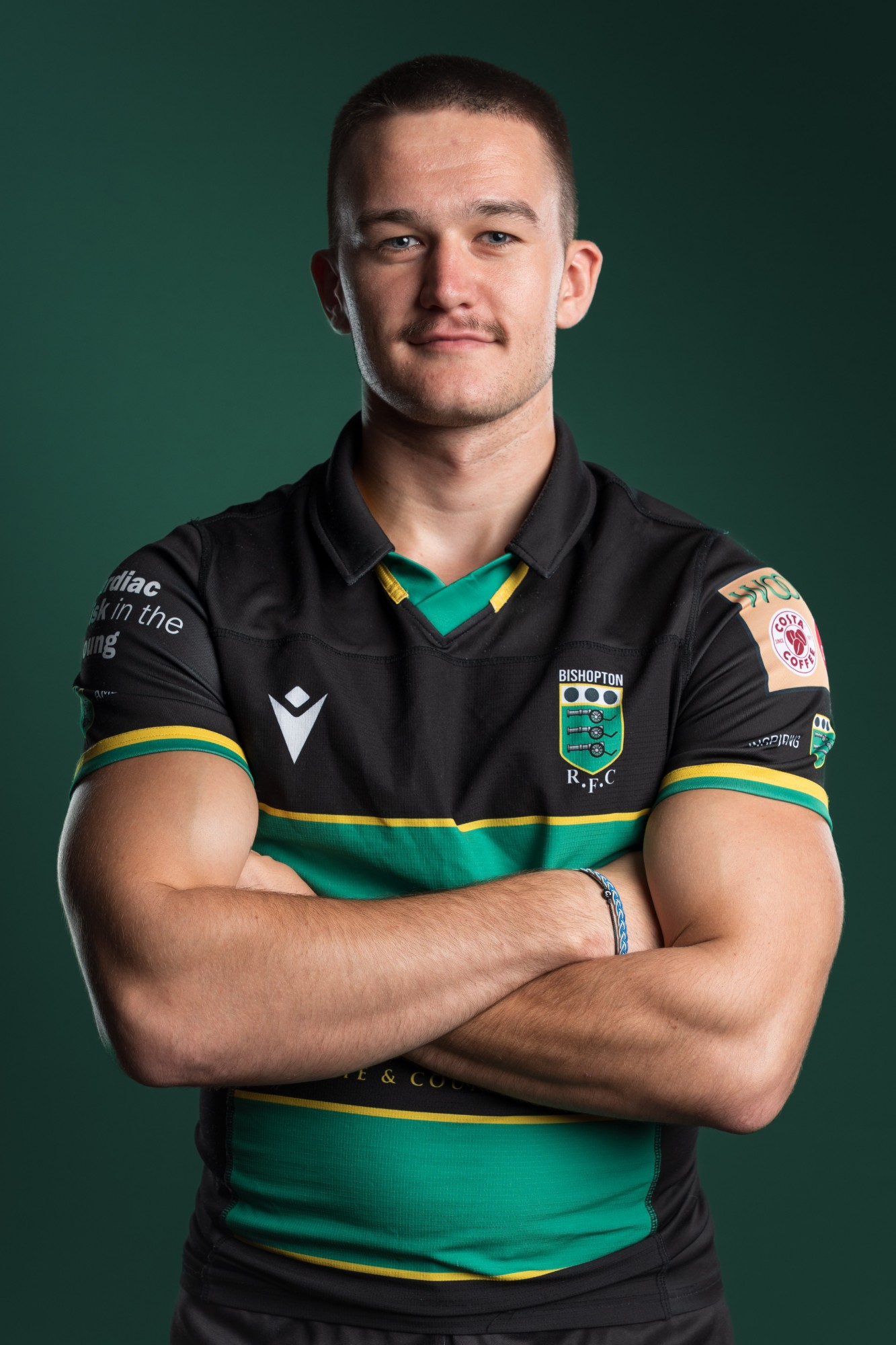 A Bishopton RFC player with his arms folded against a dark green backdrop