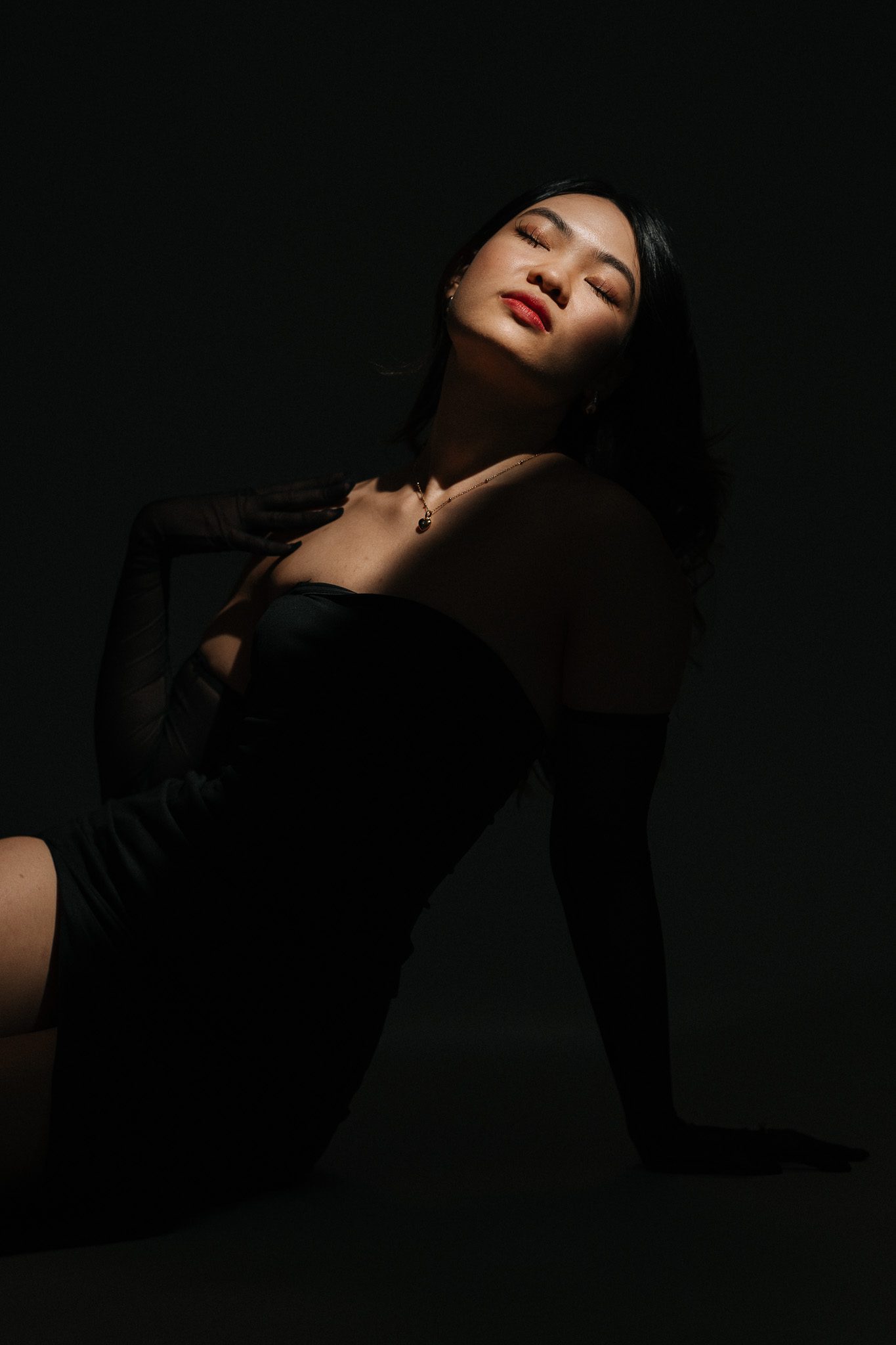 A woman in a black dress in low studio light